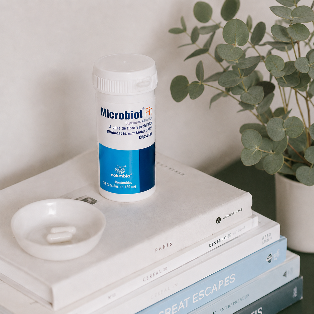 Frasco de MICROBIOT FIT sobre libros